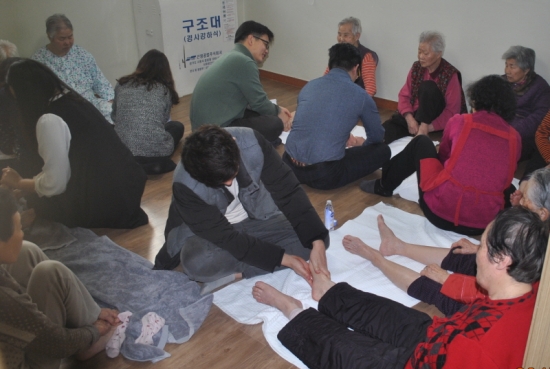 ▲GS리테일 봉사단 GS나누미가 구립영등포실버케어센터에서 어르신들의 발을 주물러 드리며 담소를 나누고 있다.(사진제공=GS리테일)