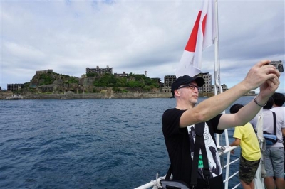 ▲일본 하시마섬(군함도)를 찾은 관광객이 섬을 배경으로 기념사진을 찍고 있는 모습. 뉴시스