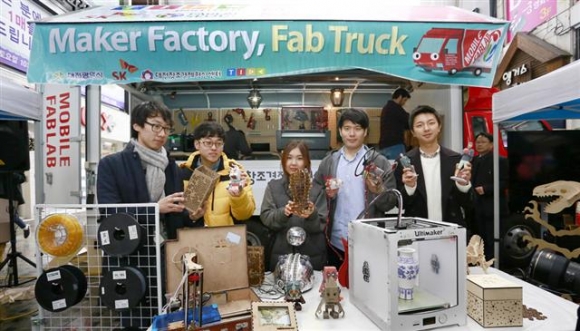 ▲지난 16일 대전시 은행동 문화거리에서 SK그룹과 대전창조경제혁신센터가 개최한 팹트럭 대전 출범식 참가자들이 3D프린터 앞에서 시제품을 들어 보이고 있다.