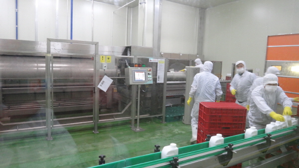 ▲흥국에프엔비 음성 공장에서 직원들이 쥬스 용기를 초고압살균기에 옮기고 있다. 