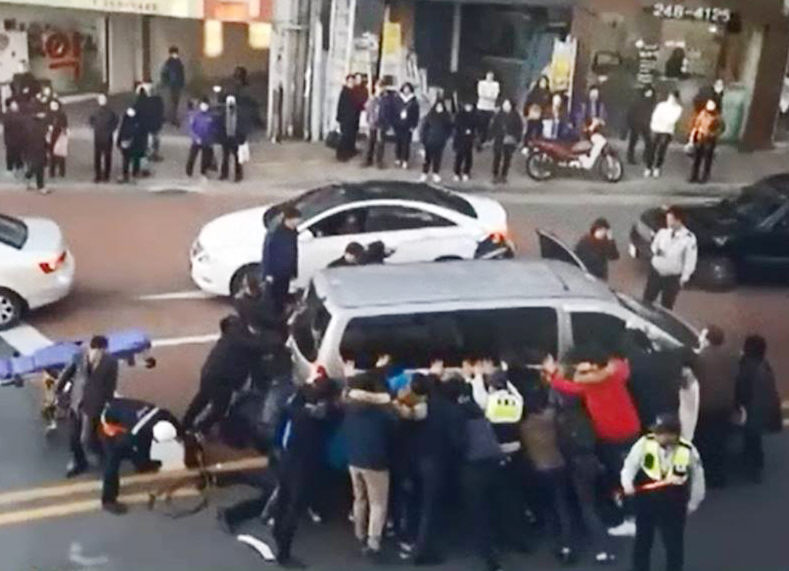 ▲교통사고가 나서 승합차에 깔린 오토바이 운전자를 지나가는 시민이 힘을 모아 구한 일이 뒤늦게 알려졌다. 29일 오후 4시 20분께 부산 중구 국제시장 인근 사거리 왕복 4차로에서 승합차 밑에 깔린 오토바이 운전자를 구하기 위해 시민과 경찰이 합세해 승합차를 들어올리고 있다.(사진=연합뉴스)