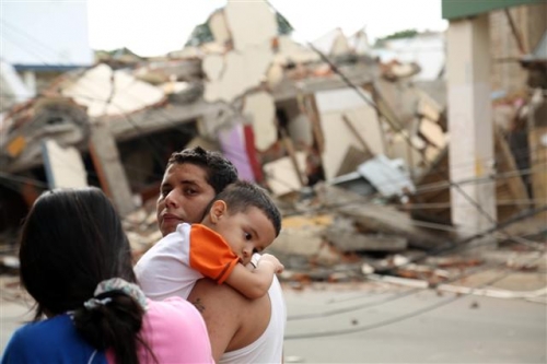 ▲에콰도르 마나비 주의 주도인 포르토비에호 시에서 17일(현지시간) 지진으로 붕괴된 집 앞에서 한 남성이 아이를 안고 있다. 포르토비에호/AP뉴시스 