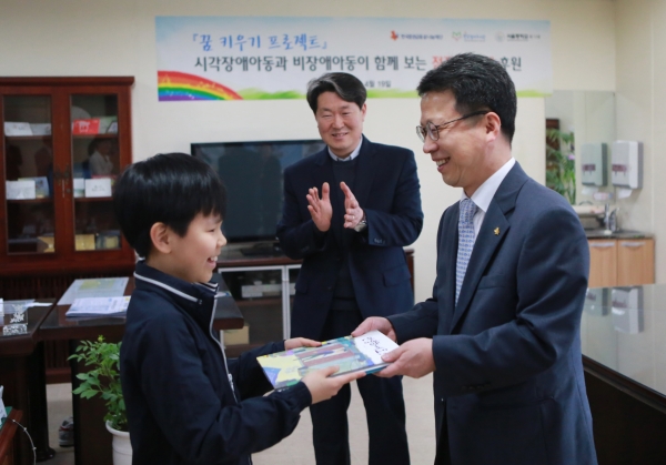 ▲19일 한국증권금융꿈나눔재단 정지원 이사장(오른쪽)이 서울 맹학교 전교학생회장 김지명 군에게 점자동화책을 전달 하고 있다.(사진제공=한국증권금융)