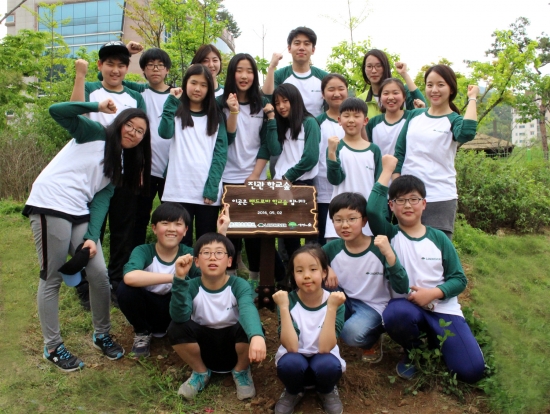 ▲금강제화가 5월 2일 서울 은평구에 위치한 진관초등학교에서 나무심기 행사를 펼치고 ‘랜드로바 학교 숲’을 기증했다. 학생들이 함께 나무를 심은 후에 사진을 찍고 있다.(사진제공=금강제화)