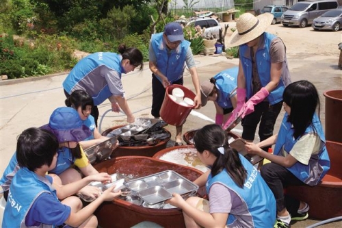 ▲한국가스공사 가족봉사단이 지난해 8월 본사가 있는 대구 인근 사회복지시설에서 식기 세척 등 단체봉사를 하고 있다.  사진제공 가스공사