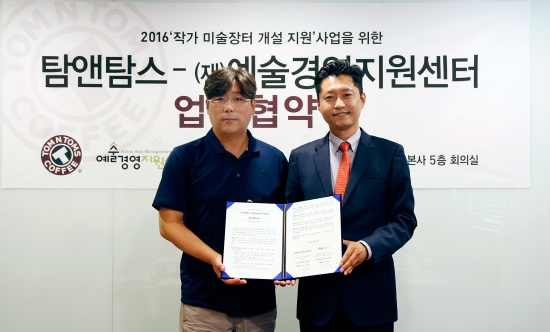 ▲김도균 탐앤탐스 대표(오른쪽)와 예술경영지원센터의 김선영 대표가 작가 미술장터 개설 지원 사업을 위한 업무협약을 체결하고 함께 사진을 찍고 있다.  
(사진제공=탐앤탐스)