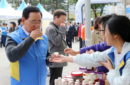 ▲27일 서울 중구 소재 신한은행 본점에서 열린 '결연마을과 함께하는 신한 따뜻한 장터'에서 신한금융그룹 한동우 회장이(사진 왼쪽) 농산품 판매장을 돌아보며 지역 특산품을 시음하고 있다.(사진=신한금융)