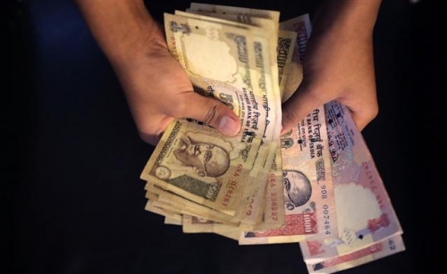▲한 인도 주민이 뉴델리에서 8일(현지시간) 500루피와 1000루피 지폐를 손에 쥐고 세고 있다. 뉴델리/AP뉴시스 