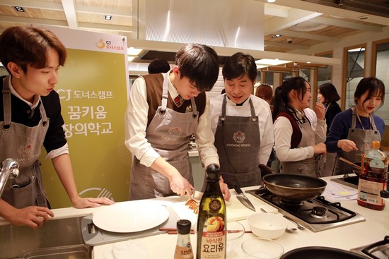 ▲CJ그룹은 24일 청소년들의 꿈을 후원하는 '꿈키움창의학교' 요리수업에 이연복 셰프(오른쪽 세 번째)를 초청해 학생들에게 진로의 꿈을 키워주는 기회를 제공했다. 이 셰프가 학생들 요리 수업을 지도하고 있다.(사진제공=CJ그룹)