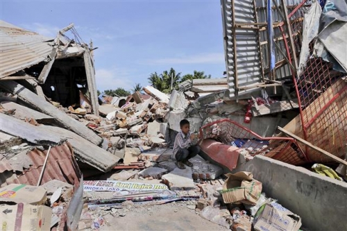 ▲인도네시아 아체 주에서 7일(현지시간) 규모 6.5 지진이 발생한 가운데 한 소년이 붕괴된 건물 잔해 위에 앉아 있다. 미국 지질조사국(USG)은 지진 규모를 당초 6.4에서 6.5로 상향 수정했다. 아체/AP뉴시스 