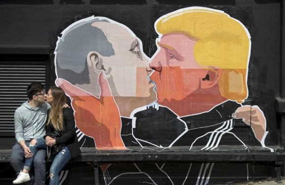 ▲리투아니아 빌니우스에 있는 한 바의 담벼락에 블라디미르 푸틴 러시아 대통령과 도널드 트럼프 미국 대통령 당선인이 격정적으로 입을 맞추는 그림이 그려져 있다. 그림 앞에서 한 커플이 그대로 따라하고 있다. 빌니우스/AP연합뉴스
