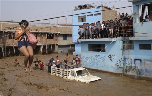 ▲페루 전역에서 폭우가 이어지는 가운데 수도 리마에서 17일(현지시간) 한 여성이 안전로프를 타고 범람한 강을 건너고 있다. 사진=AP연합뉴스