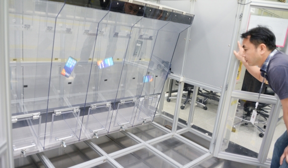 ▲LG전자 연구원이 약 1미터 높이의 투명한 사각 통에 LG G6를 넣고 끊임없이 회전시키는 '연속 낙하 시험'을 실시하고 있다. (사진제공=LG전자)