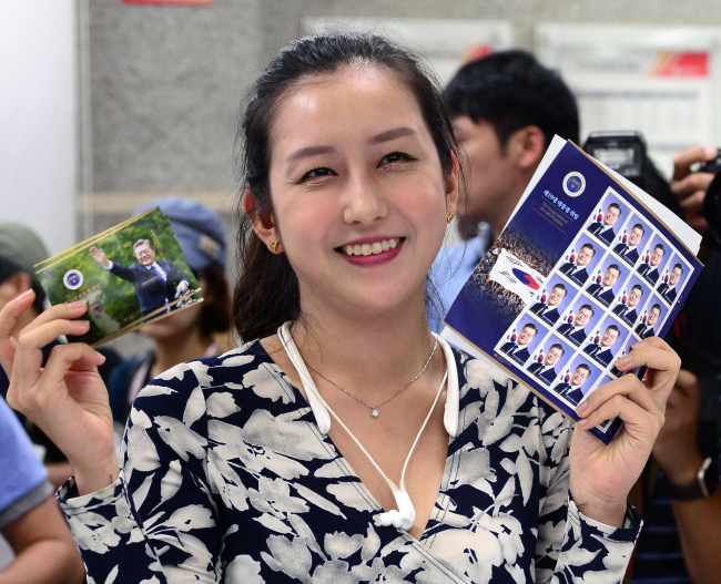 ▲문재인 대통령 취임 100일을 맞은 17일 서울 종로구 광화문우체국에서 한 시민이 문 대통령 취임 기념 우표를 구매한 후 들어보이고 있다. (뉴시스)