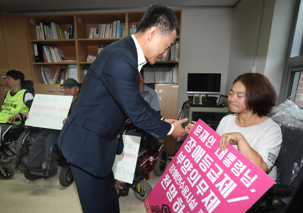 ▲박능후 보건복지부 장관이 10일 오전 빈곤가구 현장방문을 하기 전에 서울 종로구 종로장애인복지관에서 열린 간담회에서 피케팅 중인 '장애인등급제 부양의무제 폐지 광화문 공동행동' 회원들과 악수하고 있다. (연합뉴스)