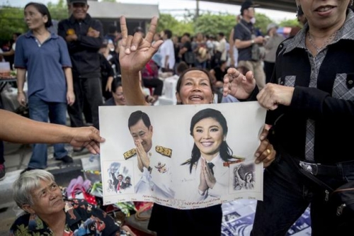 ▲태국 방콕의 대법원 앞에서 25일(현지시간) 탁신과 잉락 친나왓 전 총리 지지자들이 사진을 들고 있다. 블룸버그 