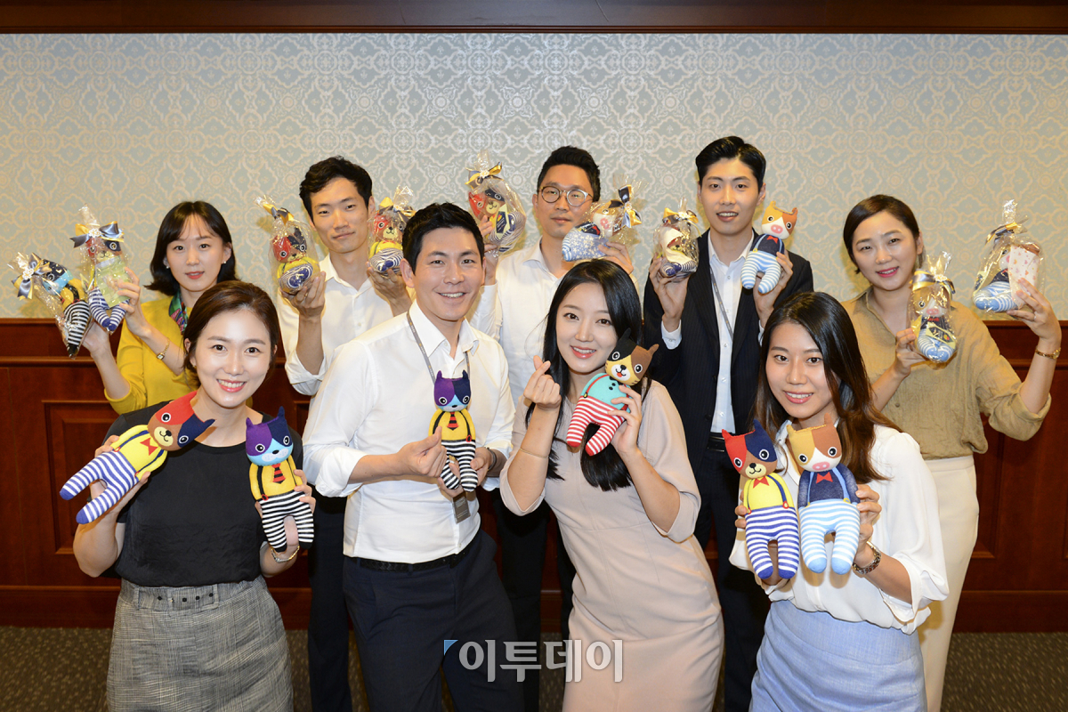 ▲이달 28일 KB증권 여의도 본사에서 직원들이 직접 만든 양말인형을 들고 기념촬영을 하고 있다. 사진제공 KB증권