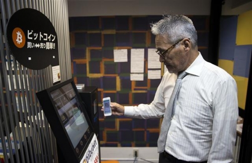 ▲일본의 한 스타트업에서 직원이 스마트폰으로 ATM 기기에서 비트코인을 인출하는 방법을 시연하고 있다. 블룸버그 