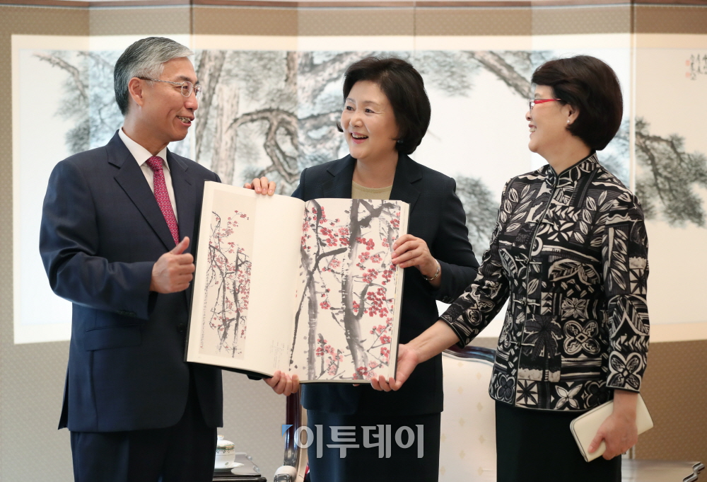▲문재인 대통령 부인인 김정숙 여사가 27일 오후 청와대 본관에서 추궈홍 주한중국대사 내외를 접견하고 한메이린 작가가 선물한 치바이스 작품전집 중 ‘홍(紅)매화’ 그림을 들고 기념촬영하고 있다.(사진제공=청와대)