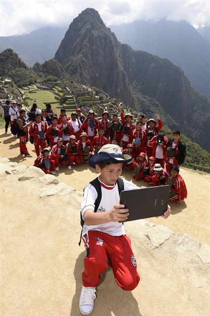 ▲페루 안데스 산맥에 위치한 ‘쿠스코 국립 과학·미술학교’ 학생들이 잉카 문명의 수도이자 잃어버린 공중도시 '마추픽추'를 배경으로 삼성전자 태블릿을 활용해 기념 촬영을 하고 있다.(사진제공=삼성전자)