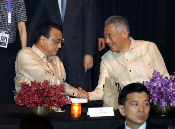 ▲ 리커창(왼쪽) 중국 총리와 리센룽 싱가폴 총리 12일 오후(현지시각) 필리핀 마닐라 몰오브아시아 SMX 컨벤션센터에서 열린 ASEAN 50주년 기념 갈라만찬에 참석해 악수하고 있다. (마닐라(필리핀)/뉴시스)