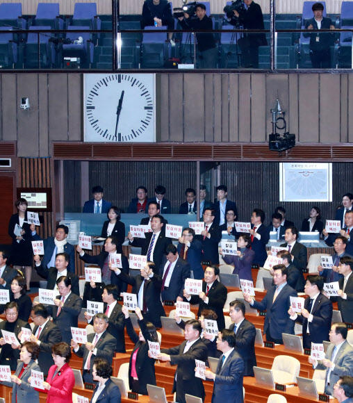 ▲6일 새벽 열린 국회 본회의에서 2018년도 예산안이 통과될 때 자유한국당 의원들이 항의 팻말을 들고 자리에 서 있다. (연합뉴스)