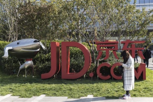 ▲한 여성이 중국 베이징의 JD닷컴 본사에 세워져 있는 마스코트 ‘조이’와 로고 옆에 서 있다. 블룸버그 
