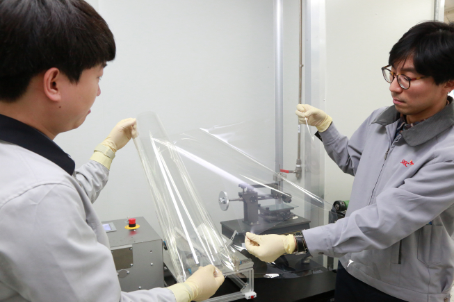 ▲SKC 투명PI 필름 R&D 담당자가 투명PI 필름을 살펴보고 있다. (사진제공=SKC)