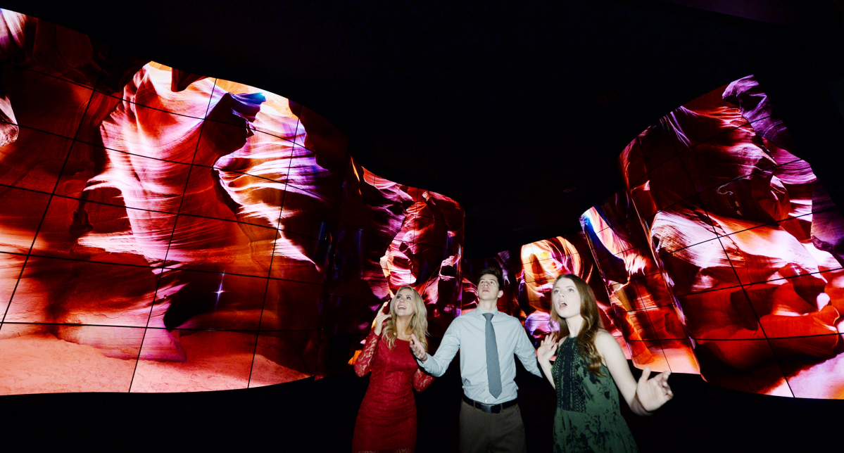 ▲LG전자가 CES 2018에서 전시장 입구에 곡면 55형 올레드 246장을 이용해 초대형 '올레드 협곡'을 설치했다. 관람객들은 총 20억 개 자발광 화소가 만들어내는 협곡, 빙하, 폭포, 숲 등 환상적인 자연 경관 영상을 감상할 수 있다. LG전자 모델들이 'LG 올레드 협곡'을 감상하고 있다.(LG전자)