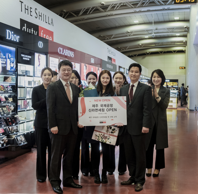 ▲신라면세점이 제주공항 국제선 면세점 오픈을 기념해 신라면세점 Korea사업부장 김태호 전무(앞줄 왼쪽)와고낙천 제주점장(앞줄 오른쪽)이 첫 구매 고객(앞줄 가운데)에게 꽃다발과 함께 선물을 증정하고 있다.(사진제공=호텔신라)