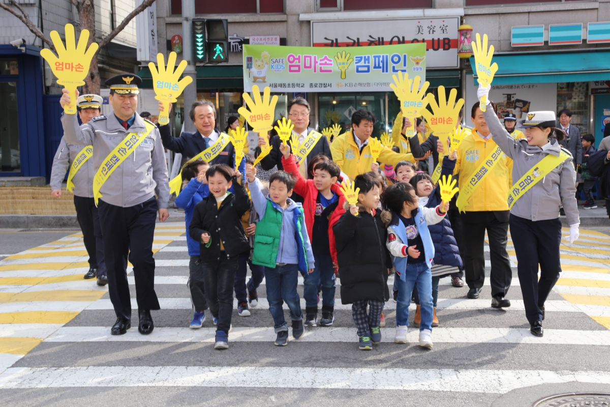 ▲재동초등학교 신입생들이 학교 인근 횡당보도에서 '엄마손' 피켓을 들고 보행안전수칙을 실습하고 있다.(사진제공=KB손해보험)