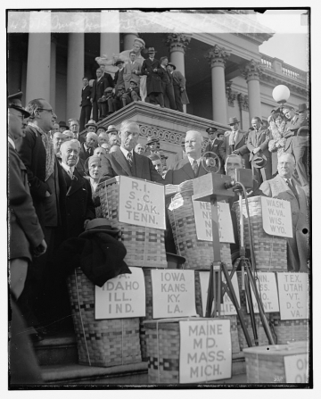 ▲1930년 스무트 홀리 관세법을 입안한 리드 스무트(왼쪽) 당시 미국 상원의원과 윌리스 홀리 하원의원이 1929년 12월 농산품을 앞에 늘어놓고 보호무역 조치를 촉구하는 연설을 하고 있다. 출처 미국 의회 도서관