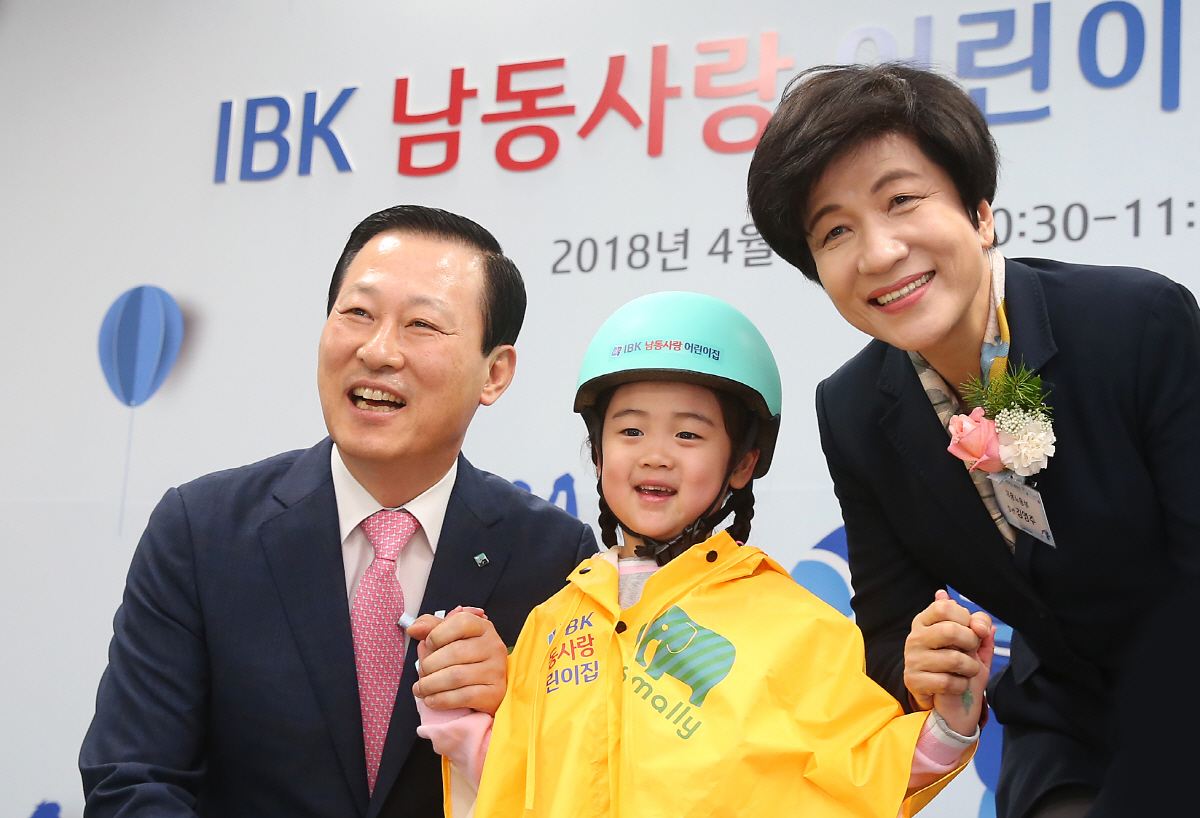 ▲김도진 은행장(왼쪽)과 김영주 고용노동부장관(오른쪽)이 IBK 남동사랑 어린이집 개원식에서 원아(임세연)에게 선물을 전달하고 기념촬영을 하고 있다.  사진제공  IBK기업은행