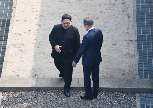 ▲27일 문재인 대통령(오른쪽)과 만난 김정은 북한 국무위원장이 판문점 군사분계선을 넘어 남한 땅에 첫 걸음을 내딛고 있다. 중국 매체들은 이 장면을 생중계하며 ‘역사적인 순간’이라고 보도했다. EPA연합뉴스
