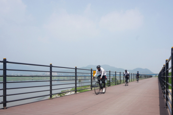 ▲SK케미칼 에코젠이 적용된 목재 플라스틱 복합재 자전거 도로 위를 자전거가  달리고 있다.(사진제공=SK케미칼)