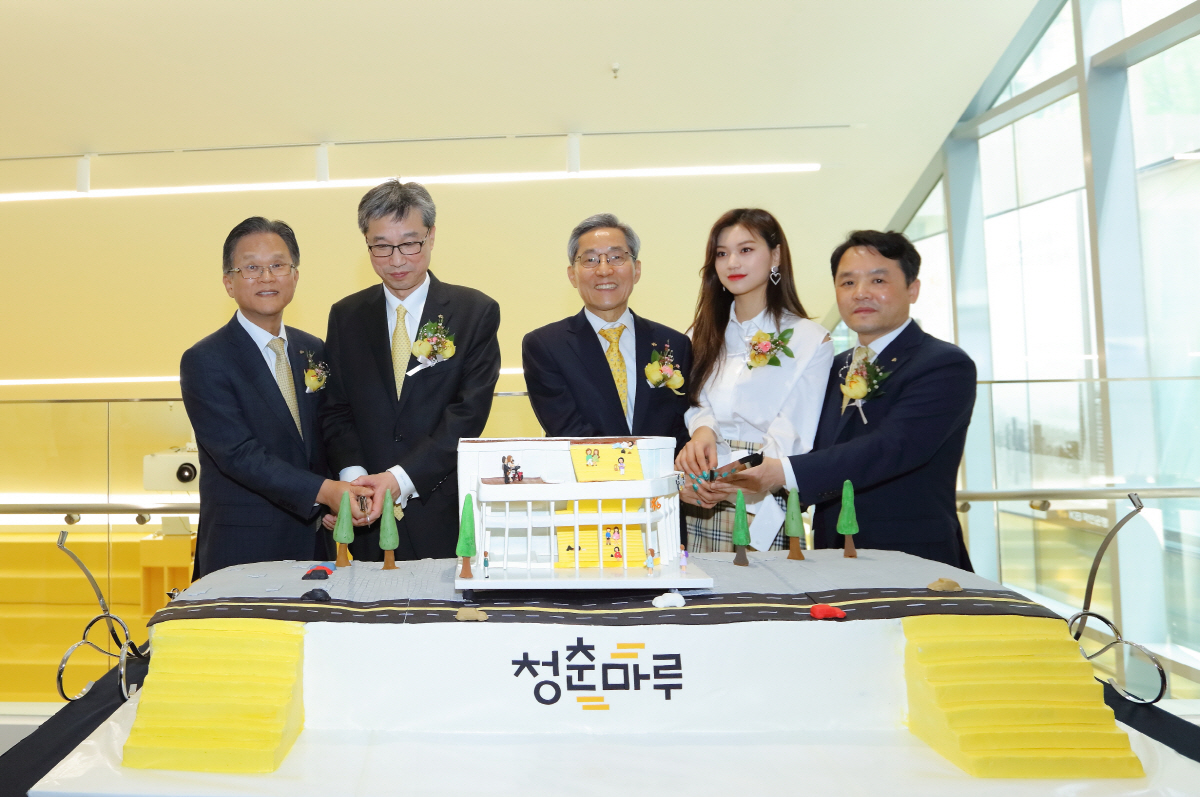 ▲윤종규 KB금융그룹 회장(가운데)이 지난달 27일 ‘KB락스타 청춘마루’개관 기념 행사에서 전귀상 KB국민은행 부행장, 허인 KB국민은행장, 걸그룹 위키미키의 멤버 김도연, 오평섭 KB국민은행 부행장(왼쪽부터) 등 참석자들과 청춘마루 건물 모양의 초대형 축하 케이크를 자르고 있다. 사진제공 KB금융