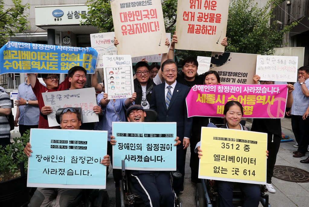 ▲문재인 대통령이 8일 오전 서울 종로구 청와대 인근 한 투표소에서 6·13 지방선거 및 국회의원 재보궐선거 사전투표를 마치고 장애인 참정권을 요구하는 장애인단체 회원들과 사진촬영을 하고 있다.(연합뉴스)