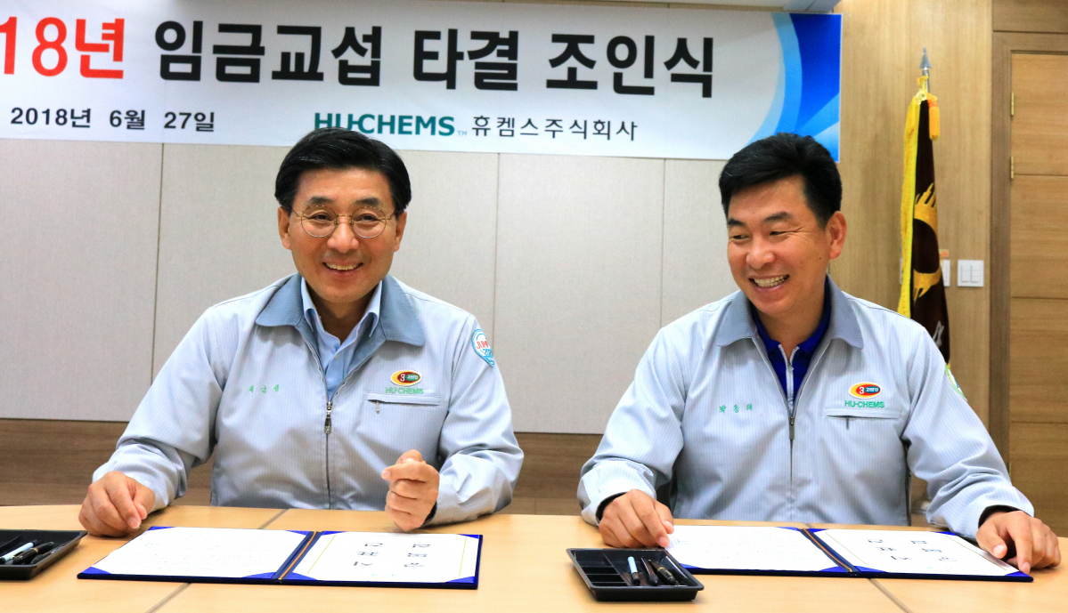 ▲27일 휴켐스 여수공장 대회의실에서 최금성 사장(왼쪽)과 박종태 노조위원장이 올해 임금협상 합의서에 사인한 후 환하게 웃고 있다. (사진제공=휴켐스)