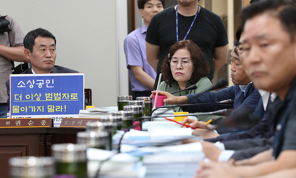 ▲10일 오후 정부세종청사 최저임금위원회에서 열린 전원회의에서 소상공인을 대표하는 권순종 소상공인연합회 부회장(왼쪽)이 '업종별 차등 적용'을 요구하는 손팻말을 들고 참석해 있다.(연합뉴스)