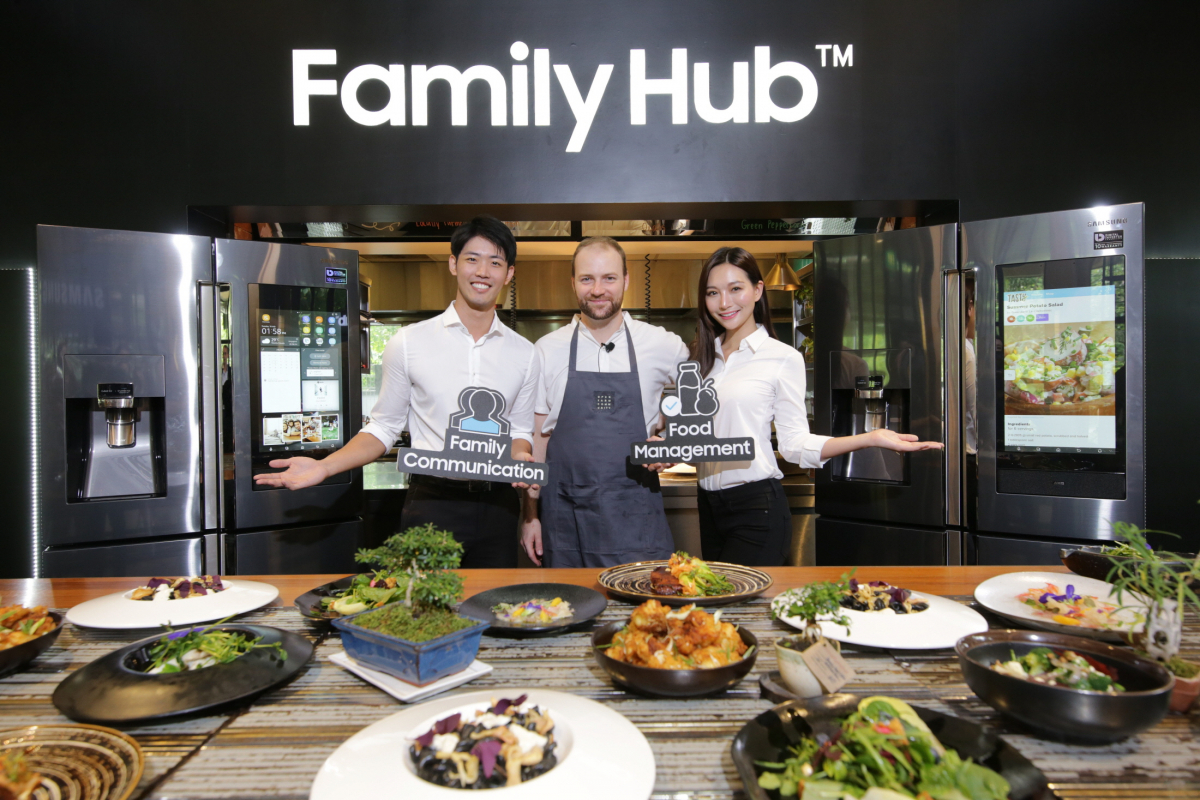 ▲유기농 요리로 유명한 캐나다 출신 올리버 트루스데일 주트라스(Oliver Truesdale-Jutras) 셰프(가운데)와 삼성전자 모델이  ‘패밀리허브’를 선보이고 있다.(사진=삼성전자)
