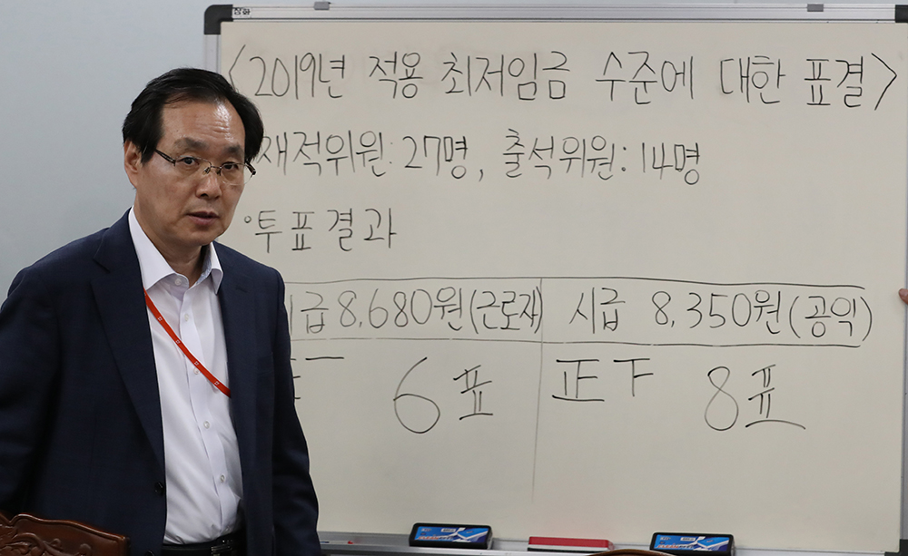 ▲14일 오전 정부세종청사 고용노동부에서 열린 최저임금위원회 전원회의에서 내년도 최저임금이 확정돼 류장수 위원장이 금액 안내판을 지나가고 있다. (연합뉴스)