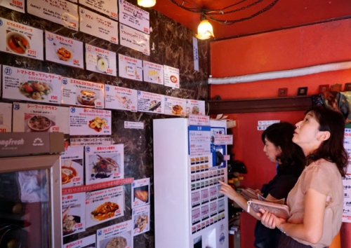 ▲일본 도쿄의 한 프렌치 레스토랑에서 고객이 벽에 붙은 사진을 보며 기계로 메뉴를 주문하고 있다. 출처 니혼게이자이신문
