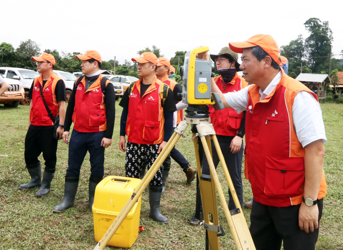 ▲최광철 SK그룹 긴급구호단장(사회공헌위원회 위원장)이 29일 라오스 아타프주 사남사이 지역 대피소에서 구호활동을 하던 중 이재민을 위해 건립할 임시숙소 부지를 측량기로 살펴보고 있다. (사진제공=SK)