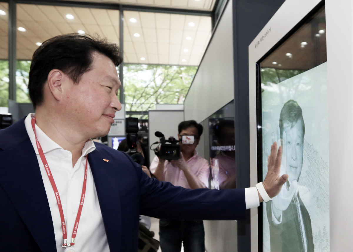 ▲최태원 SK 회장이 14일 서울 종로구 서린동 SK사옥 로비에서 개막한 최종현 SK 회장 20주기 사진전에서 키오스크(무인단말기)를 통해 SK가 지원하는 사회적기업에 기부를 하고 있다. (사진제공=SK)