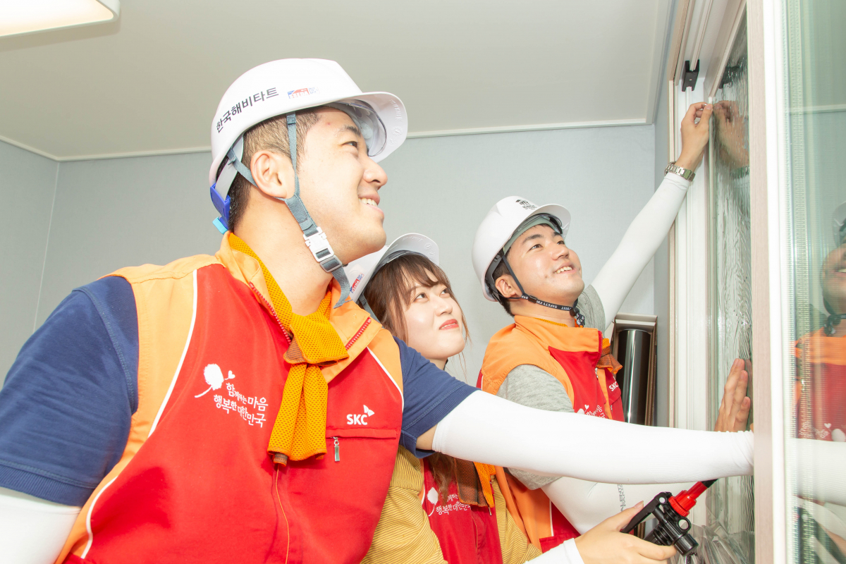 ▲SKC 프로보노단 1기 구성원이 22일 충남 천안시 한국해비타트 집짓기 현장에서 윈도우필름 시공 활동을 하고 있다. (사진 제공=SKC)