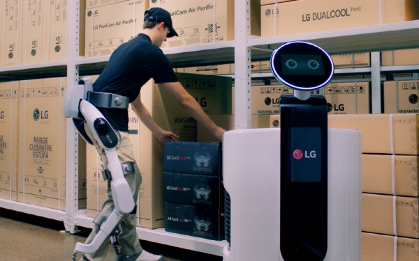 ▲‘LG 클로이 수트봇’을 착용한 작업자가 물류센터에서 상품을 쇼핑카트로봇에 옮겨담고 있는 모습. 사진제공=LG전자