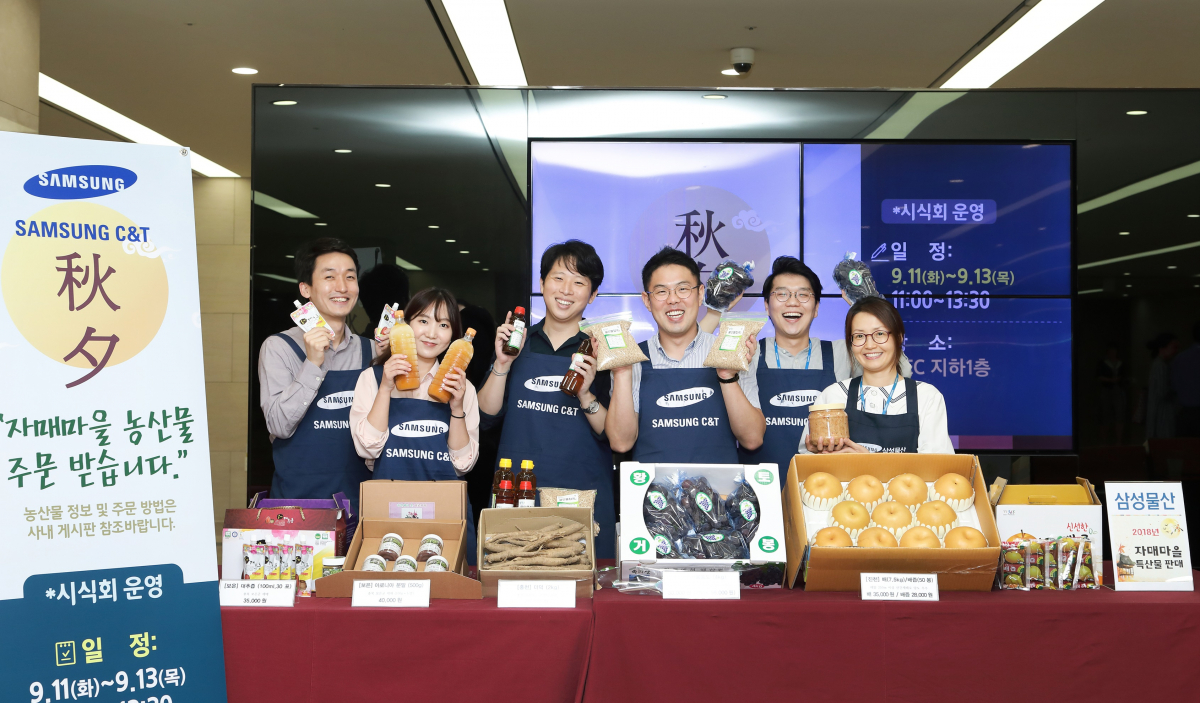 ▲삼성물산 임직원들이 자매마을 특산품을 들고 환하게 웃고 있다.(사진 제공=삼성물산)