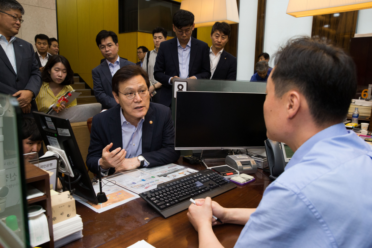 ▲최종구 금융위원장이 18일 오후 서울시 중구 KB국민은행 을지로3가 지점을 방문해 주택시장 안정대책 발표 후 현장 분위기와 준비상황을 창구 직원에게 듣고 있다.(사진=금융위원회 제공 )