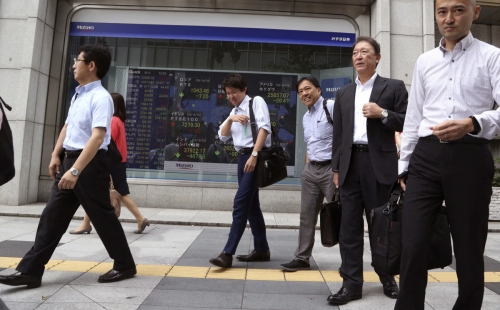 ▲11일(현지시간) 일본 도쿄에서 직장인들이 주식 전광판 앞을 걷고 있다. 도쿄/AP연합뉴스

