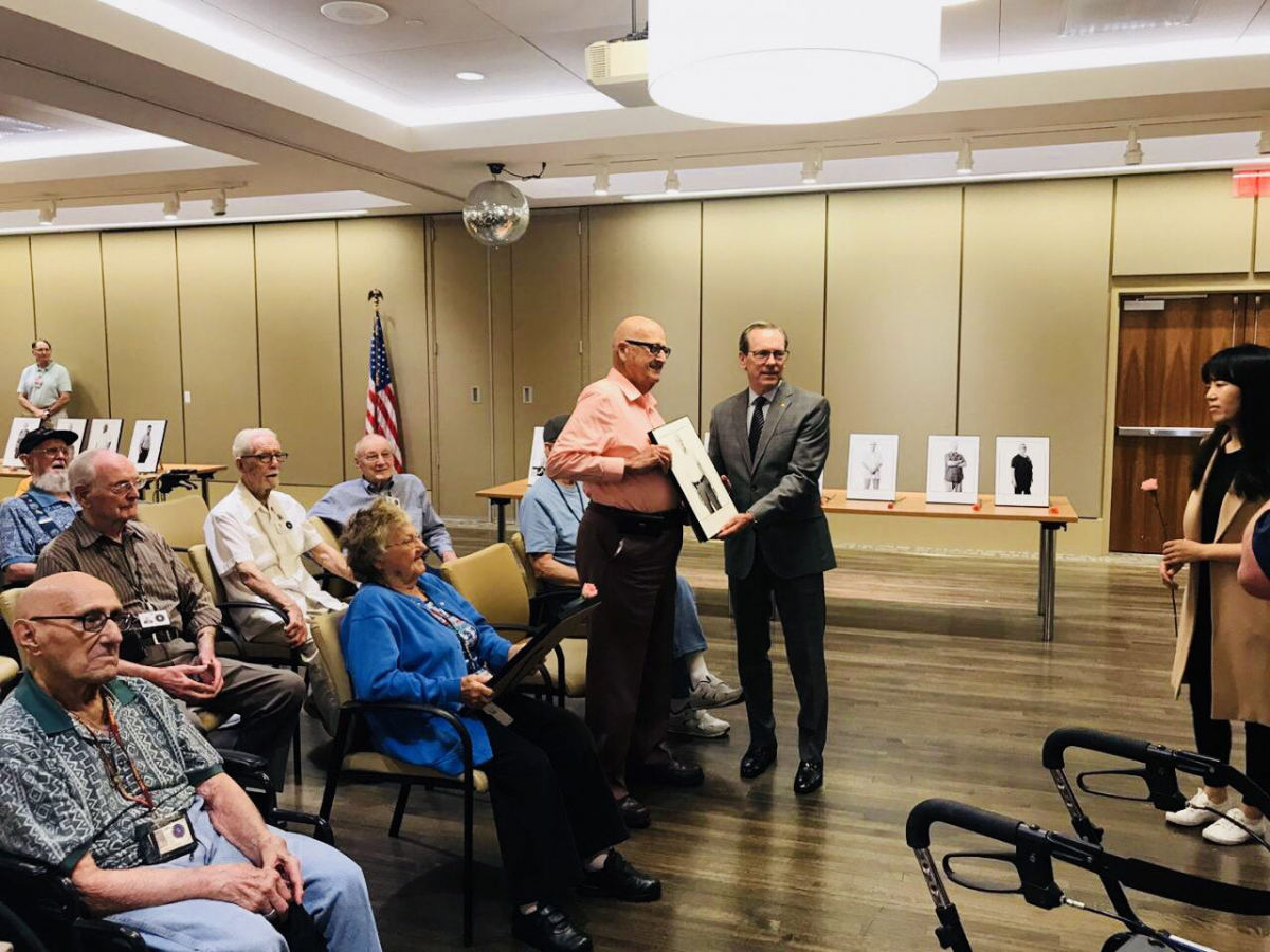 ▲전 미8군사령관 버나드 샴포 중장(현 한화 부사장)이 참전용사와 액자를 들고 기념사진을 촬영하고 있다.(사진 제공=한화)